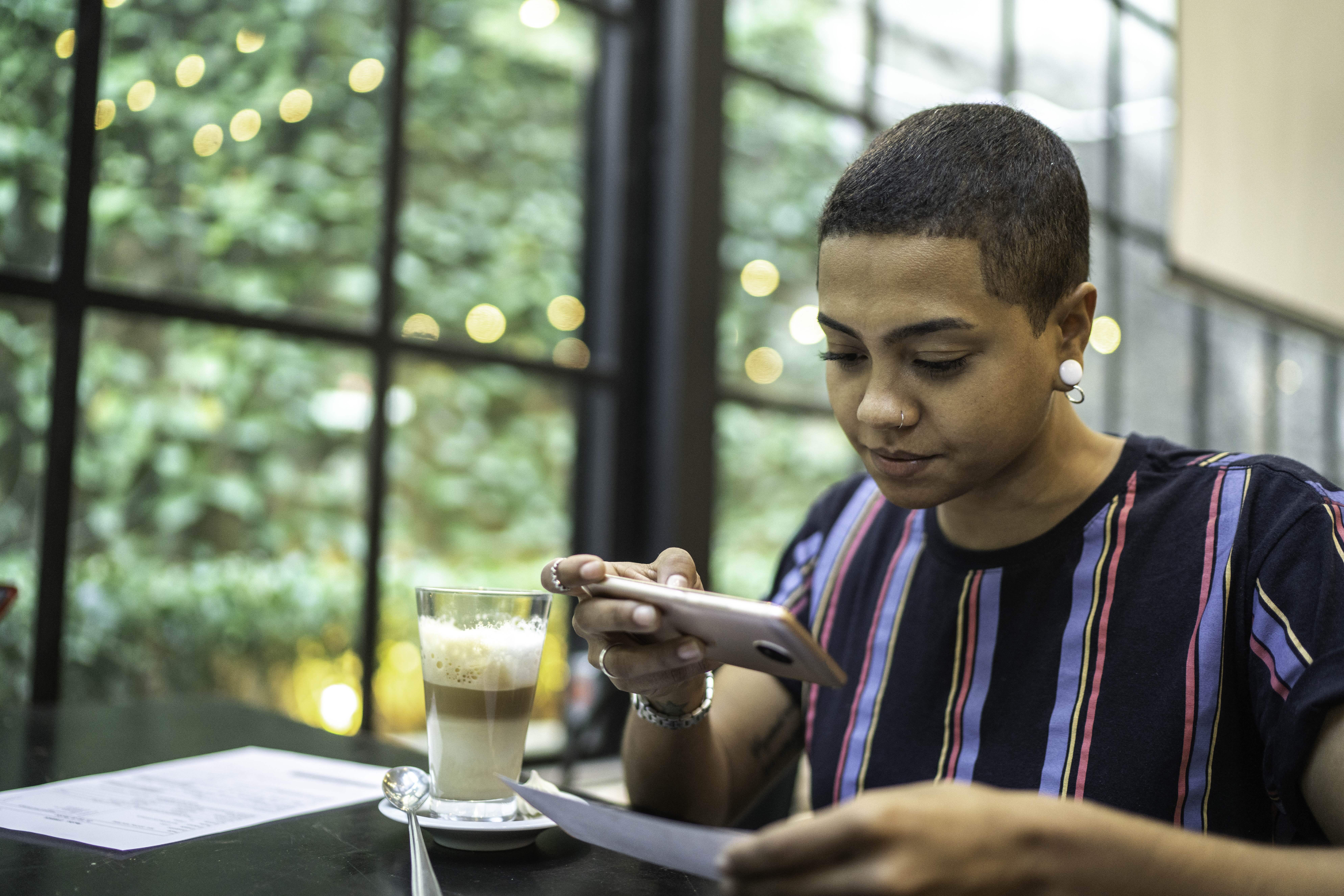 woman at a coffee shop taking a photo of a check to deposit