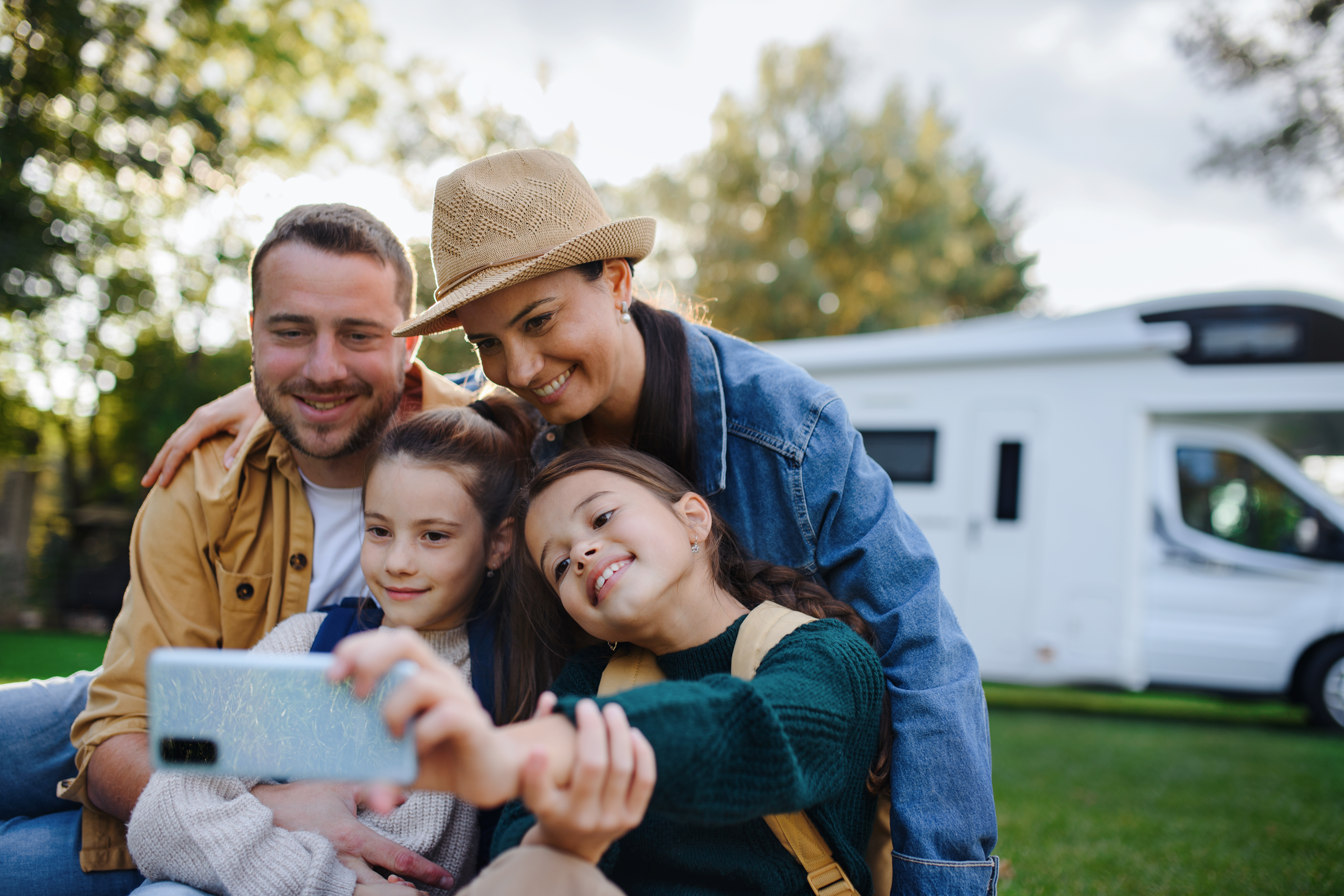 Family taking a selfie with a motor home in the background