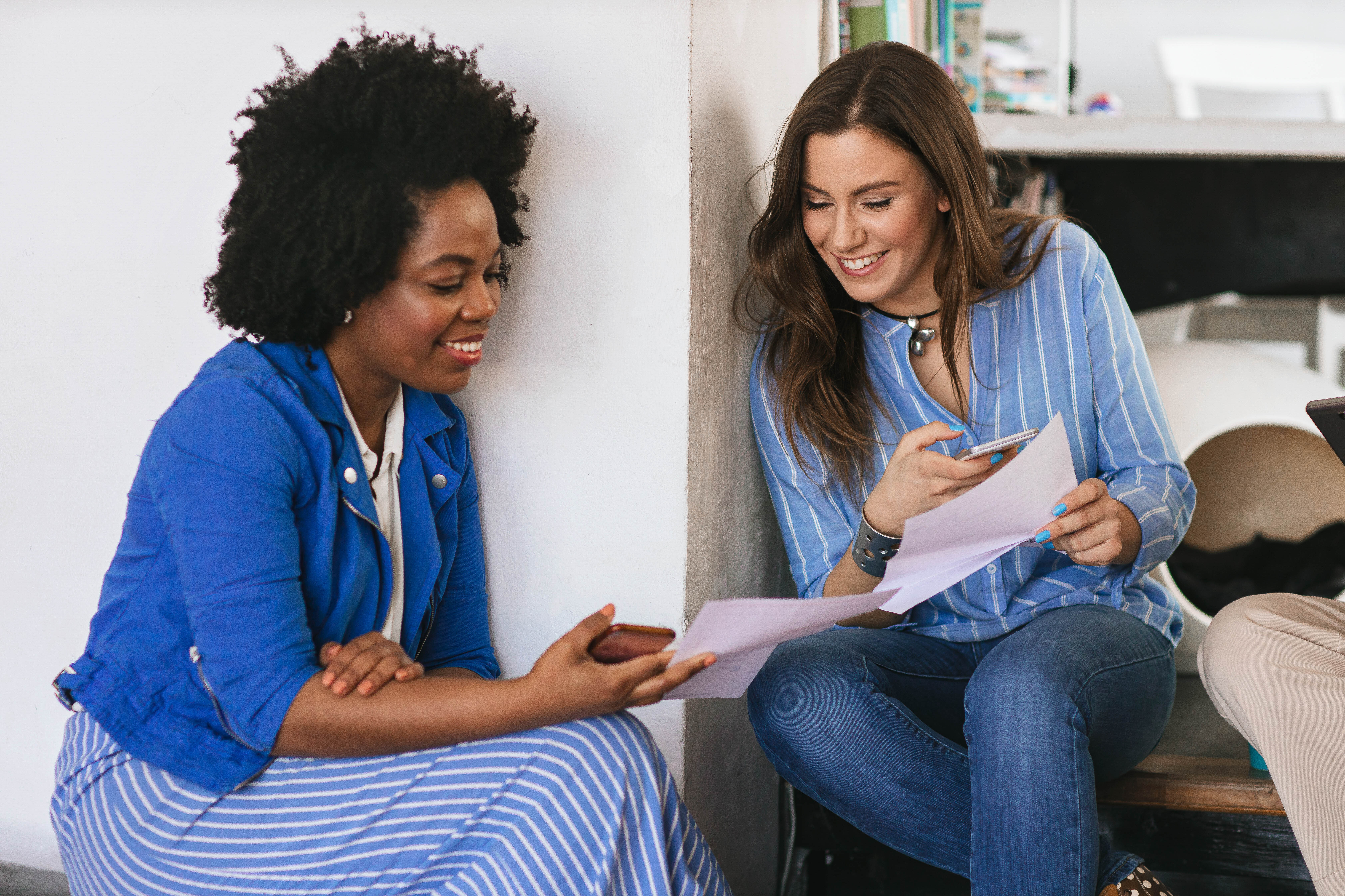 two young women paying each other on mobile phones