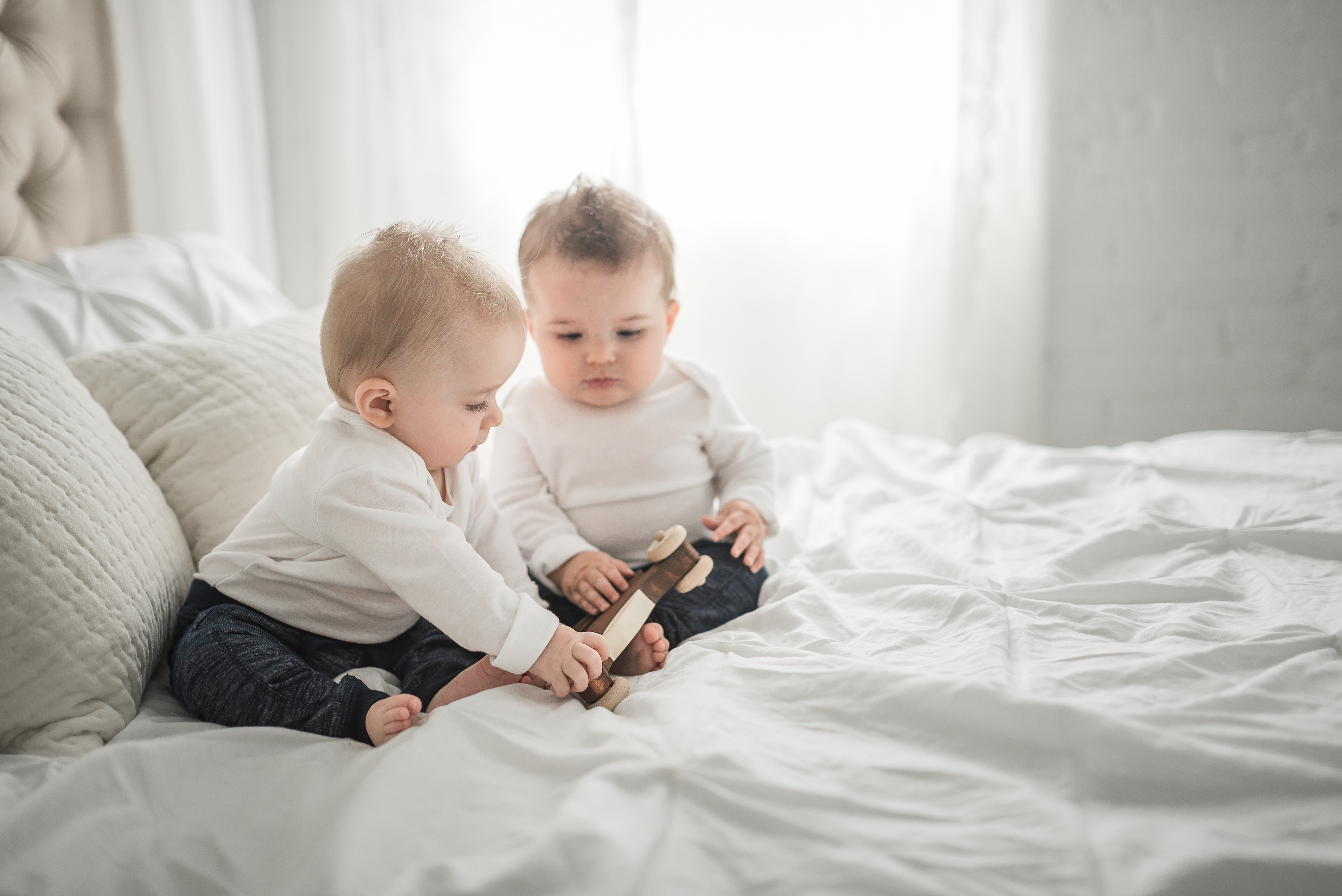 two babies sitting on a bed