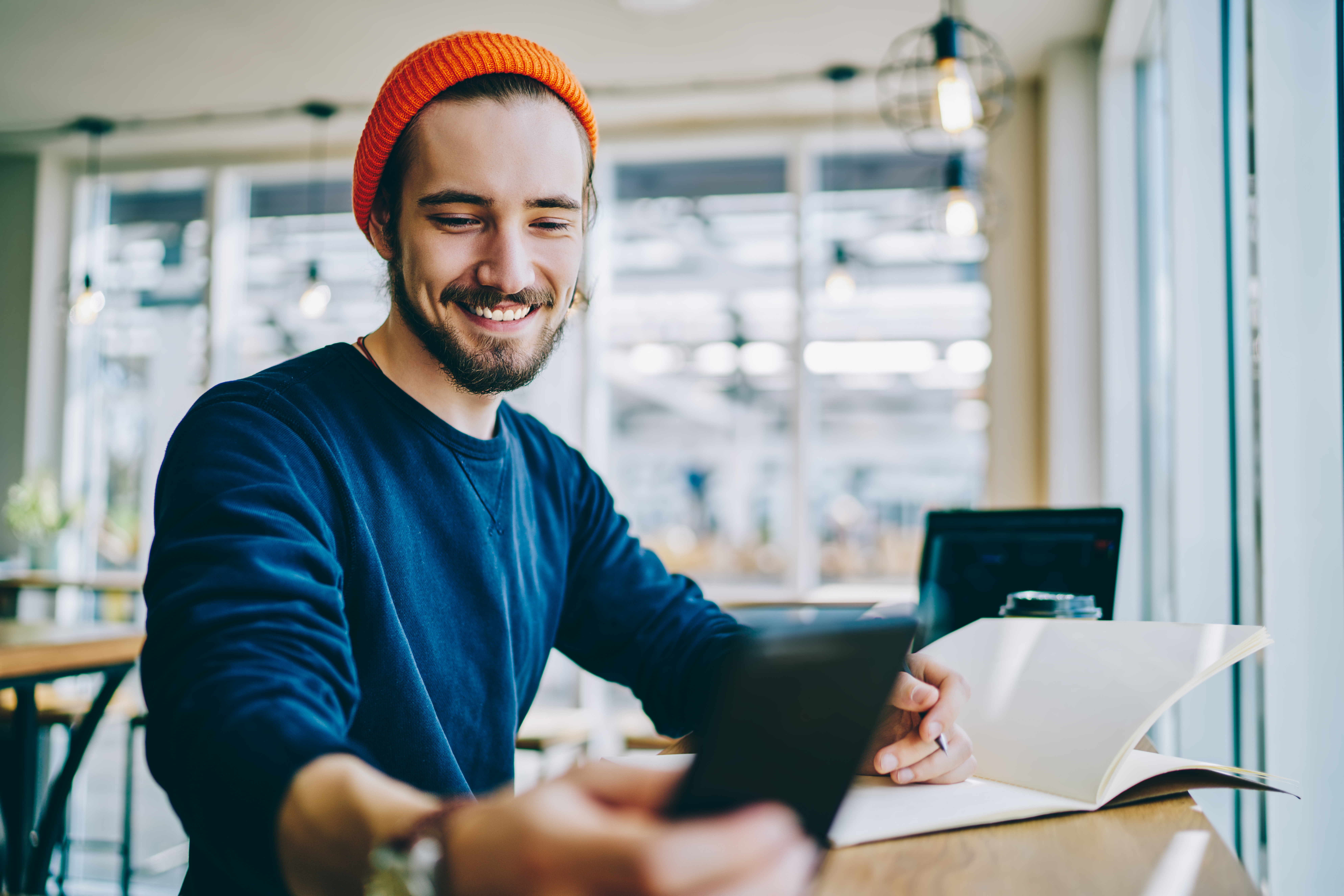 man in a coffee shop checking his phone while smiling