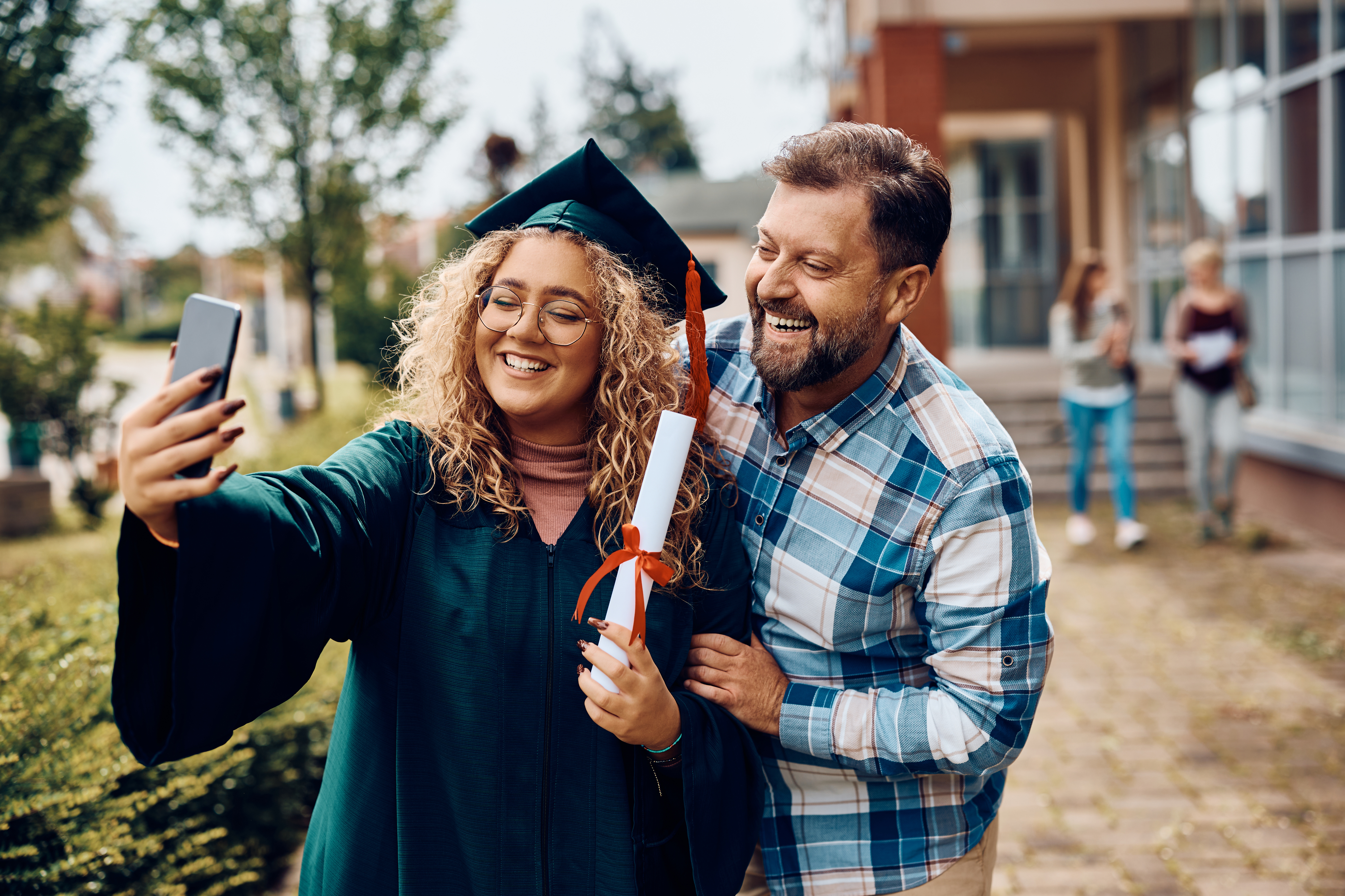 daughter graduating from school taking a selfie with her dad
