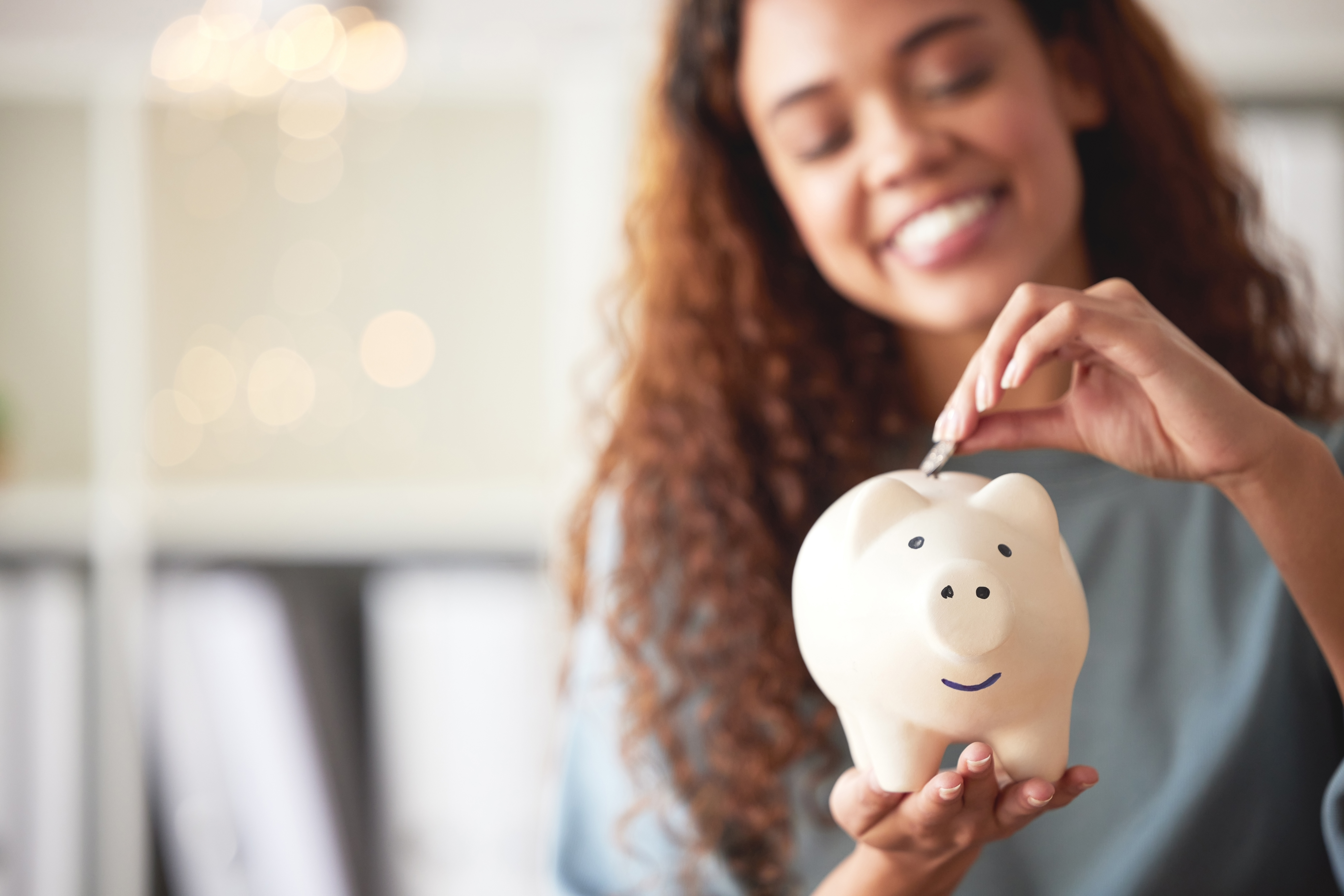 woman putting a coin in a piggy bank