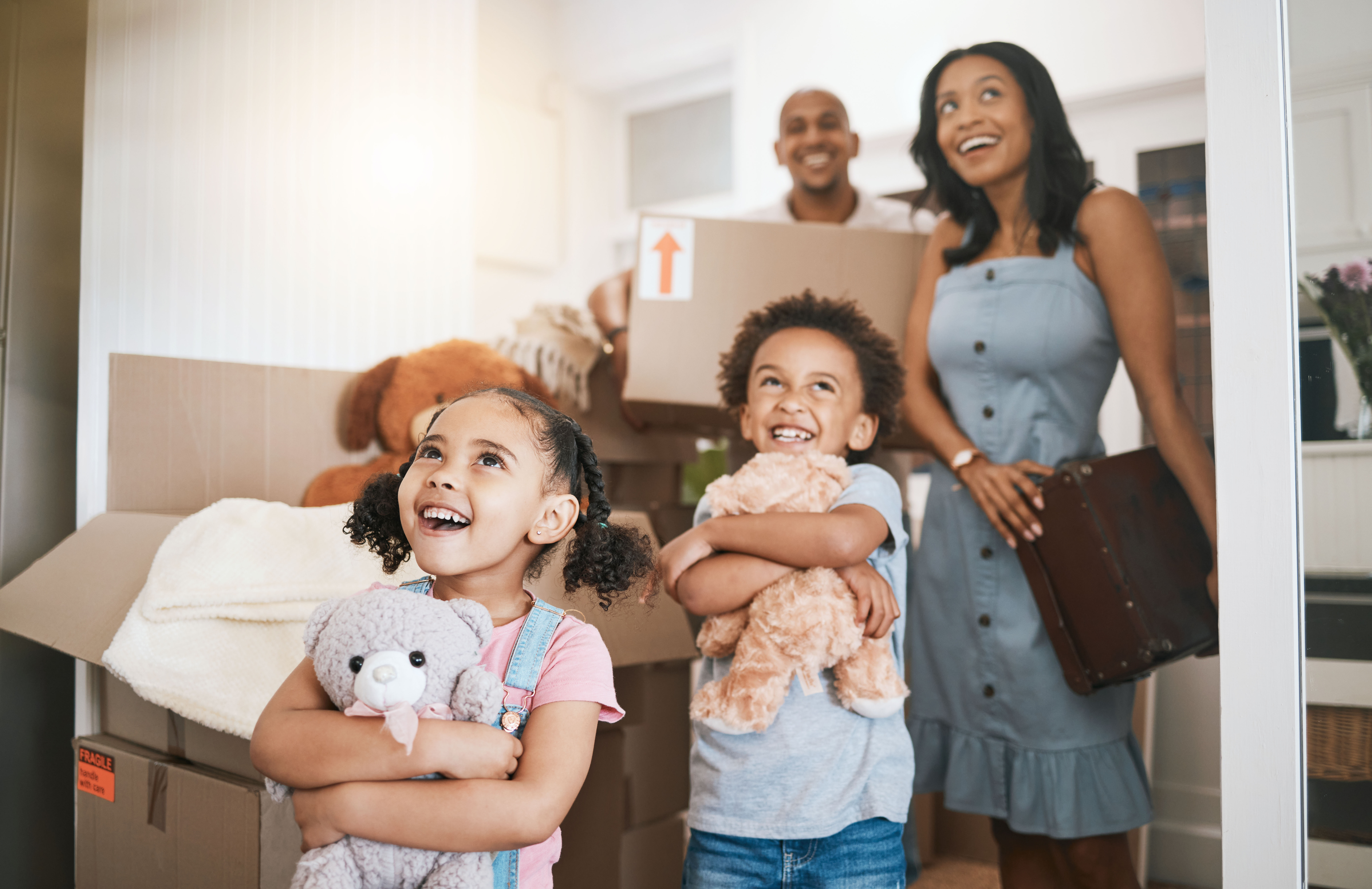 mom and dad with their young son and daughter happily moving into a new house